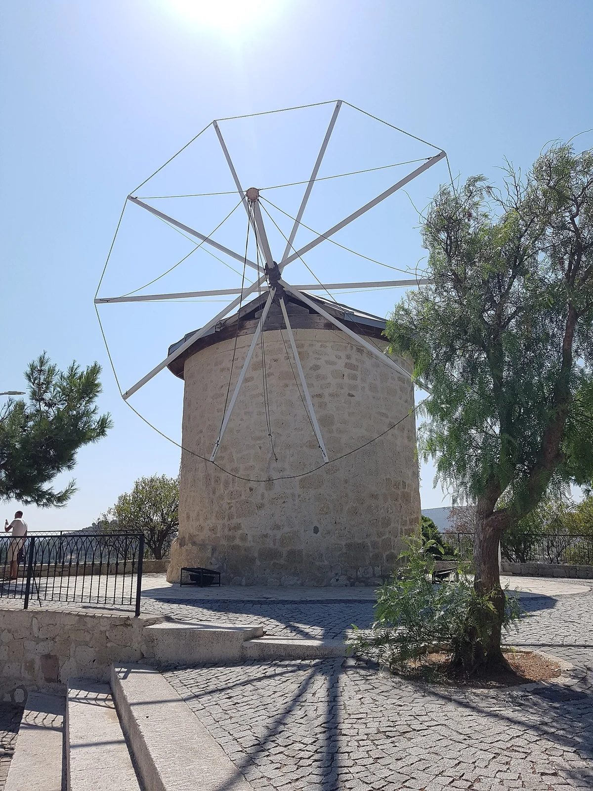 A restored stone windmill with its sails on the hill at Alaçatı