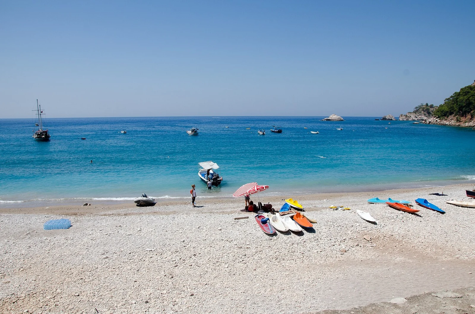 The pebble beach at Kabak with kayaks and clear blue water