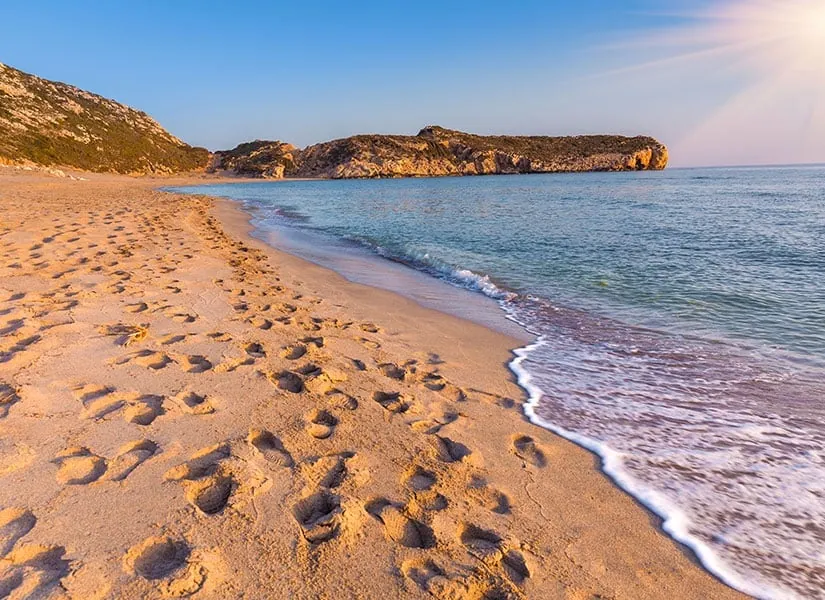 The long empty sand of Patara beach behind ancient ruins